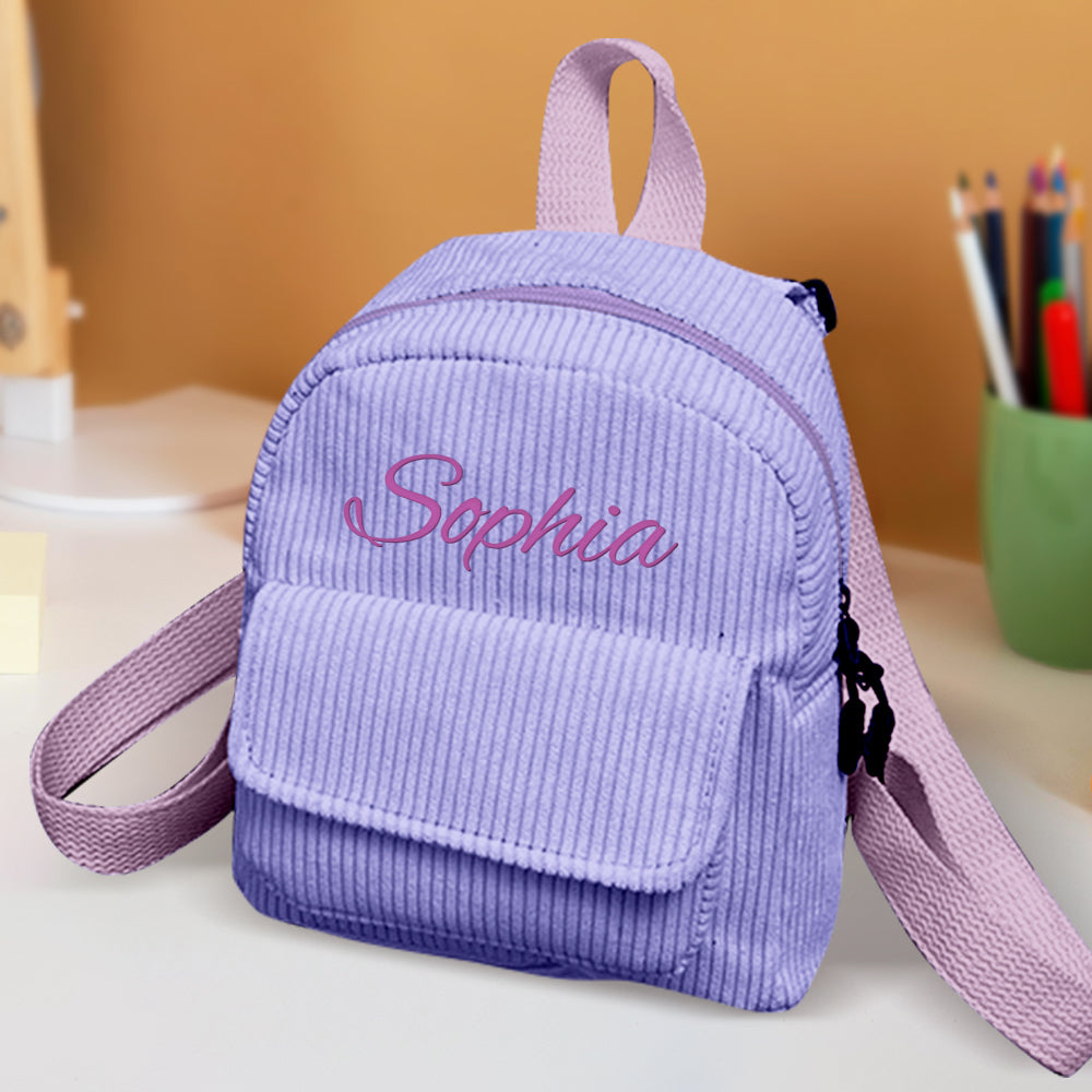 Purple corduroy backpack with 'Sophia' embroidery on a blurred background