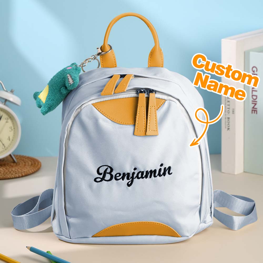Light blue backpack with yellow accents and 'Benjamin' printed on it, placed on a surface with a light blue background.