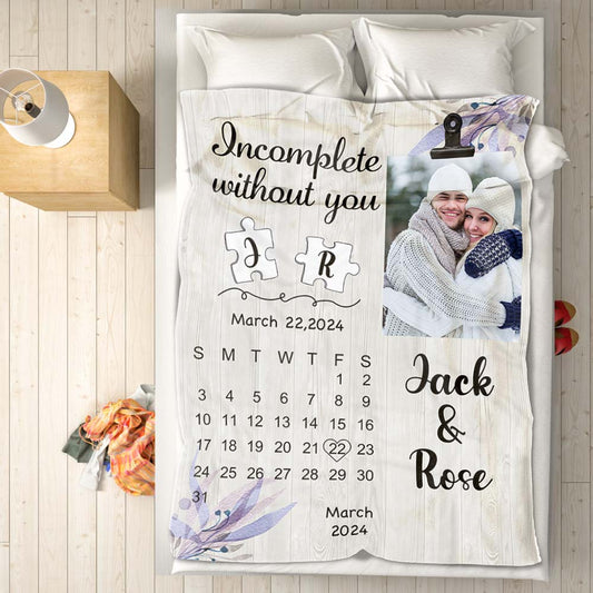 Personalized blanket with a photo of a couple, text, and a calendar on a bed.