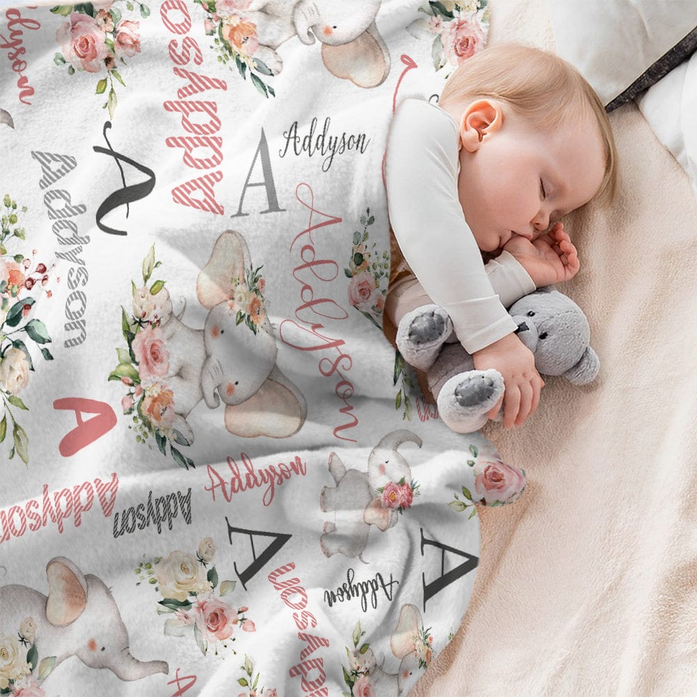 Baby sleeping with a personalized blanket featuring floral and elephant designs.
