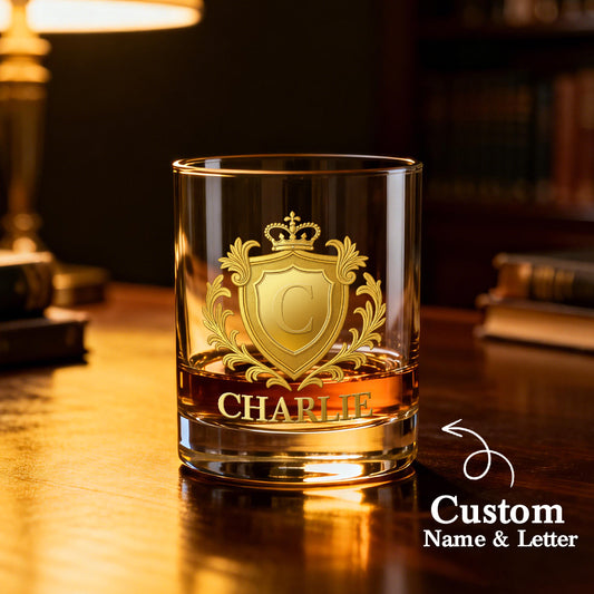 Glass with gold emblem and 'CHARLIE' engraving on a wooden surface, blurred background