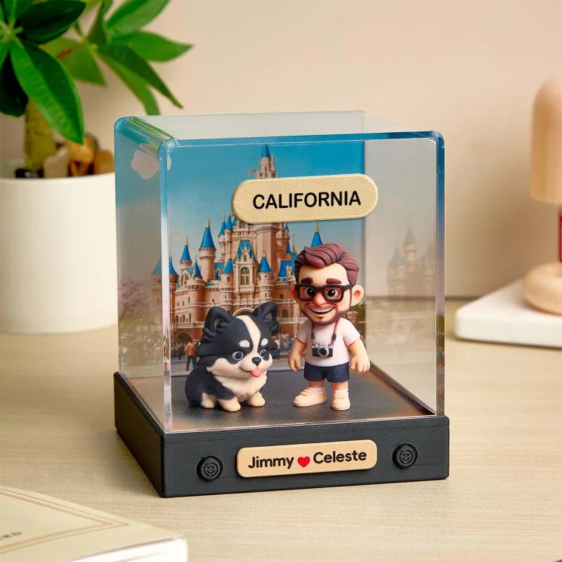 Figurines of a man and a dog with a castle in the background, labeled 'California', in a clear display case on a table.