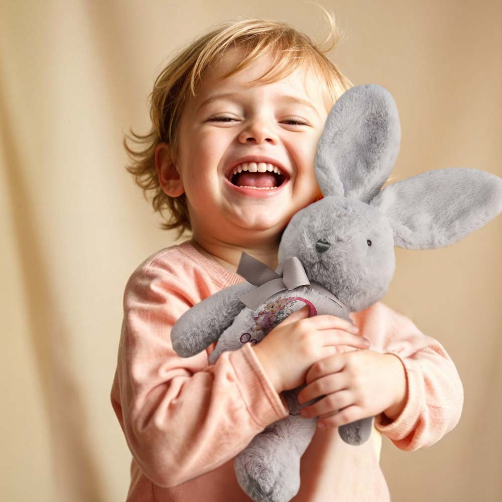 Child holding a gray plush toy with a plain background
