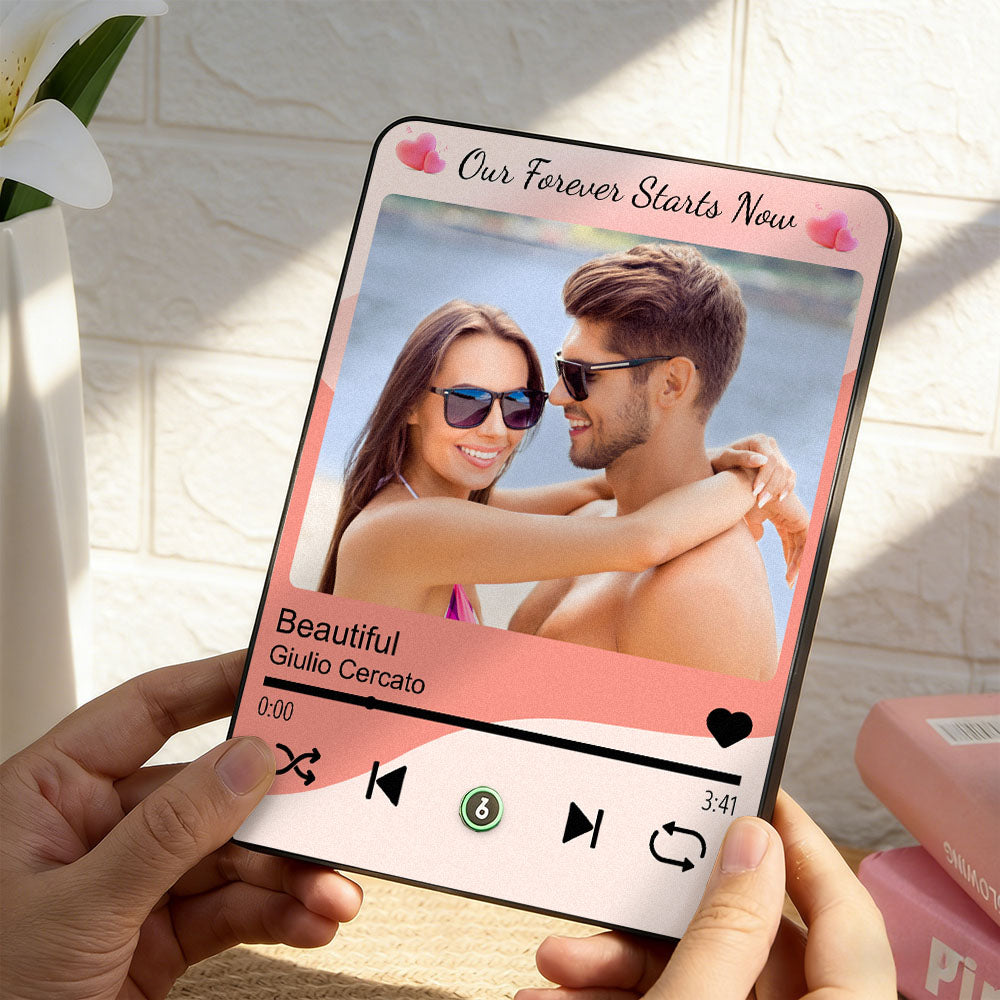 Phone displaying a romantic photo of a couple with music player interface, held by hands against a light background.