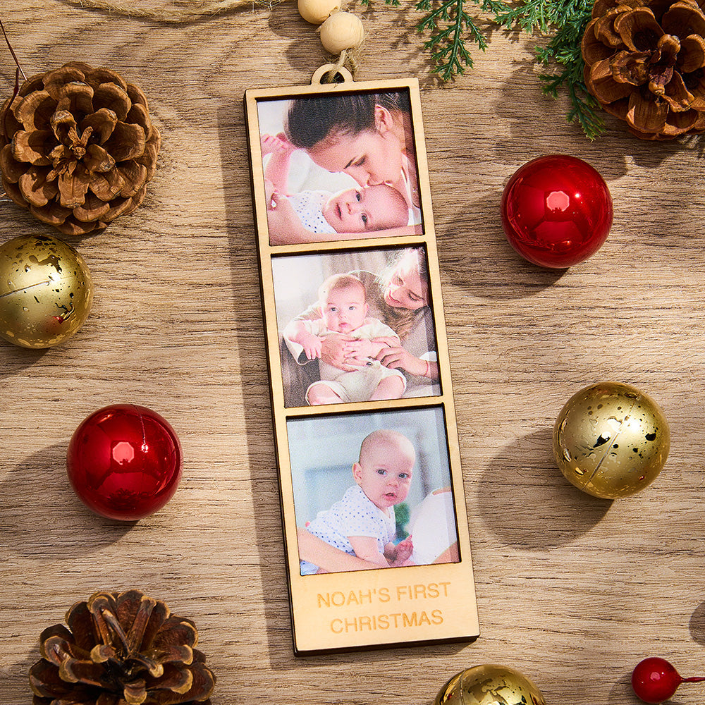 Wooden photo ornament with baby photos and 'Noah's First Christmas' text, surrounded by Christmas decorations on a wooden surface.