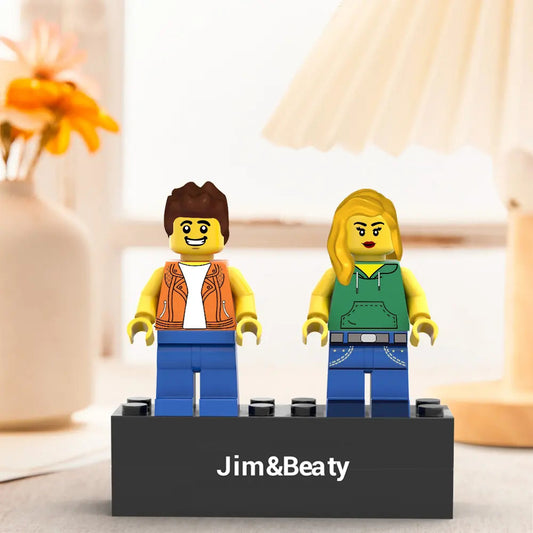 Two LEGO figures on a stand with 'Jim&Beaty' branding, set against a blurred indoor background.