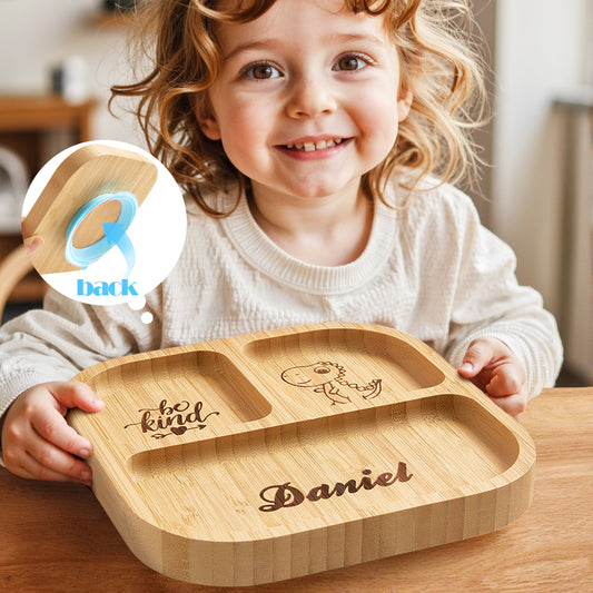 Child holding a wooden tray with engraved text, sitting at a table.