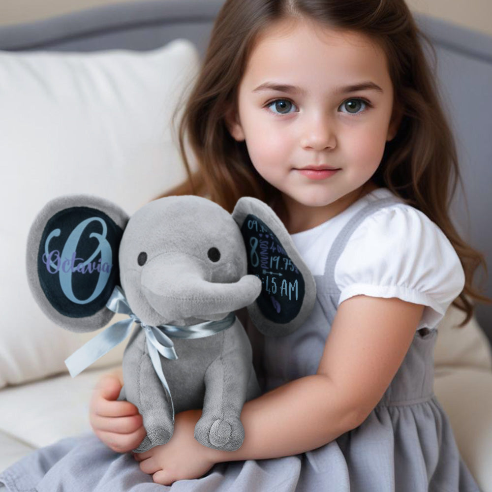 Young girl holding a gray elephant plush toy with personalized chalkboard ears.