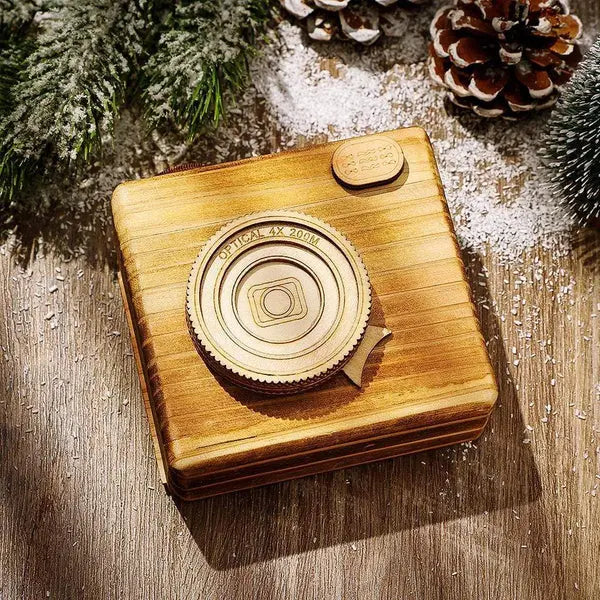 Wooden camera model on a wooden surface with pine cones and branches in the background