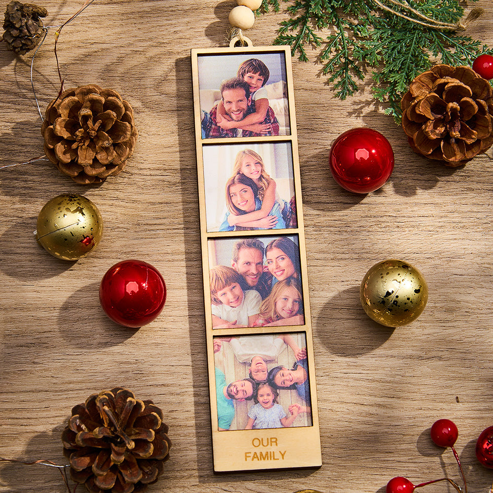 Wooden photo display with family photos surrounded by Christmas decorations on a wooden surface.