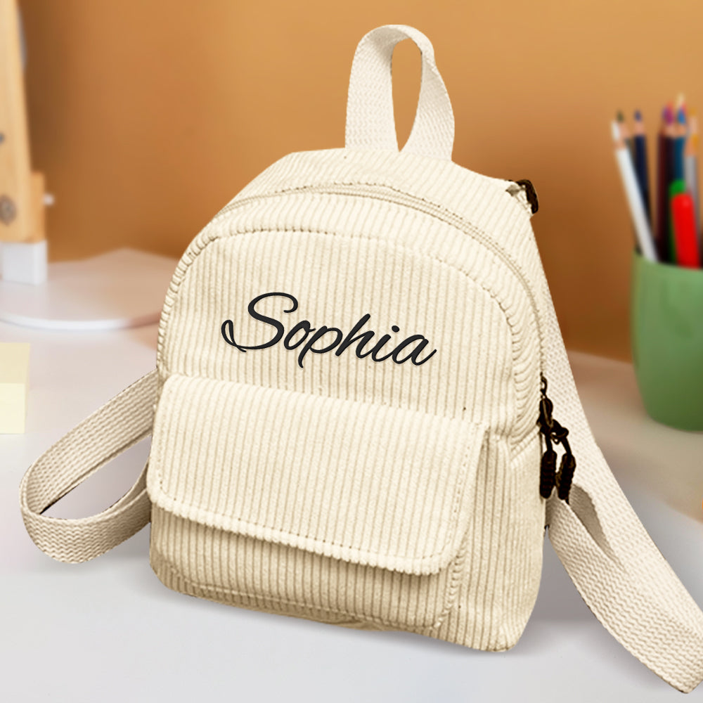 Beige corduroy backpack with 'Sophia' embroidery on a blurred background