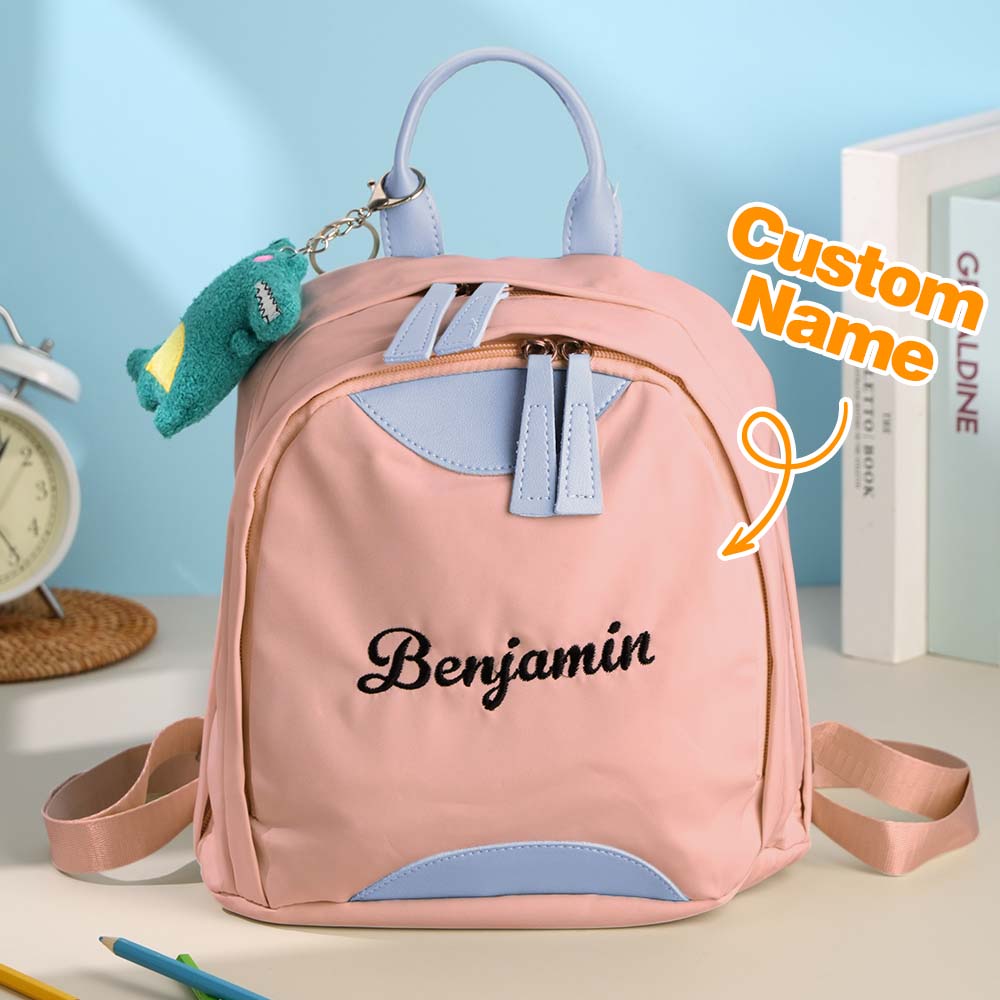Pink backpack with 'Benjamin' name on it, sitting on a surface with books and stationery items.