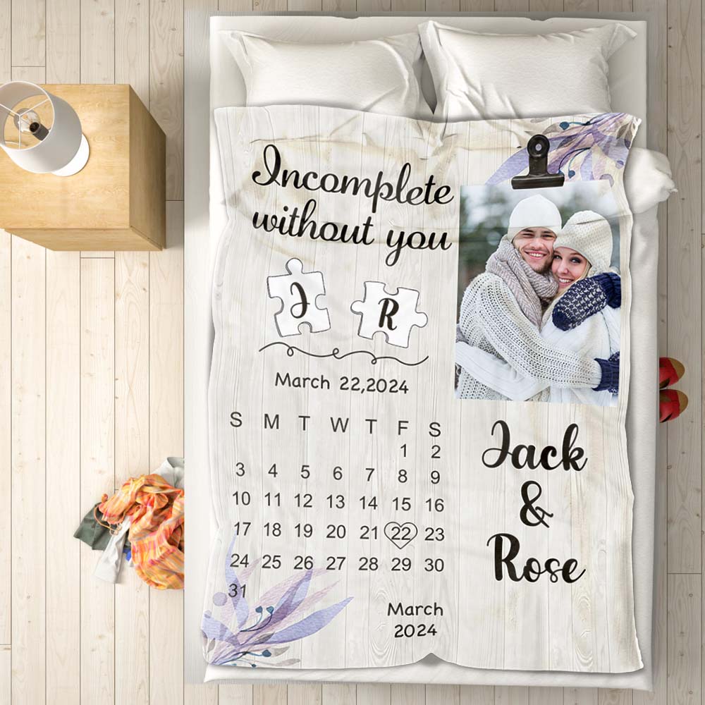 Personalized blanket with a photo of a couple, text, and a calendar on a bed.