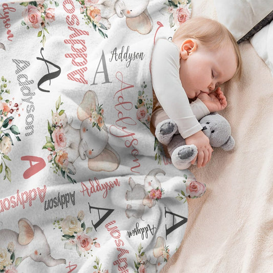 Baby sleeping with a personalized blanket featuring floral and elephant designs.