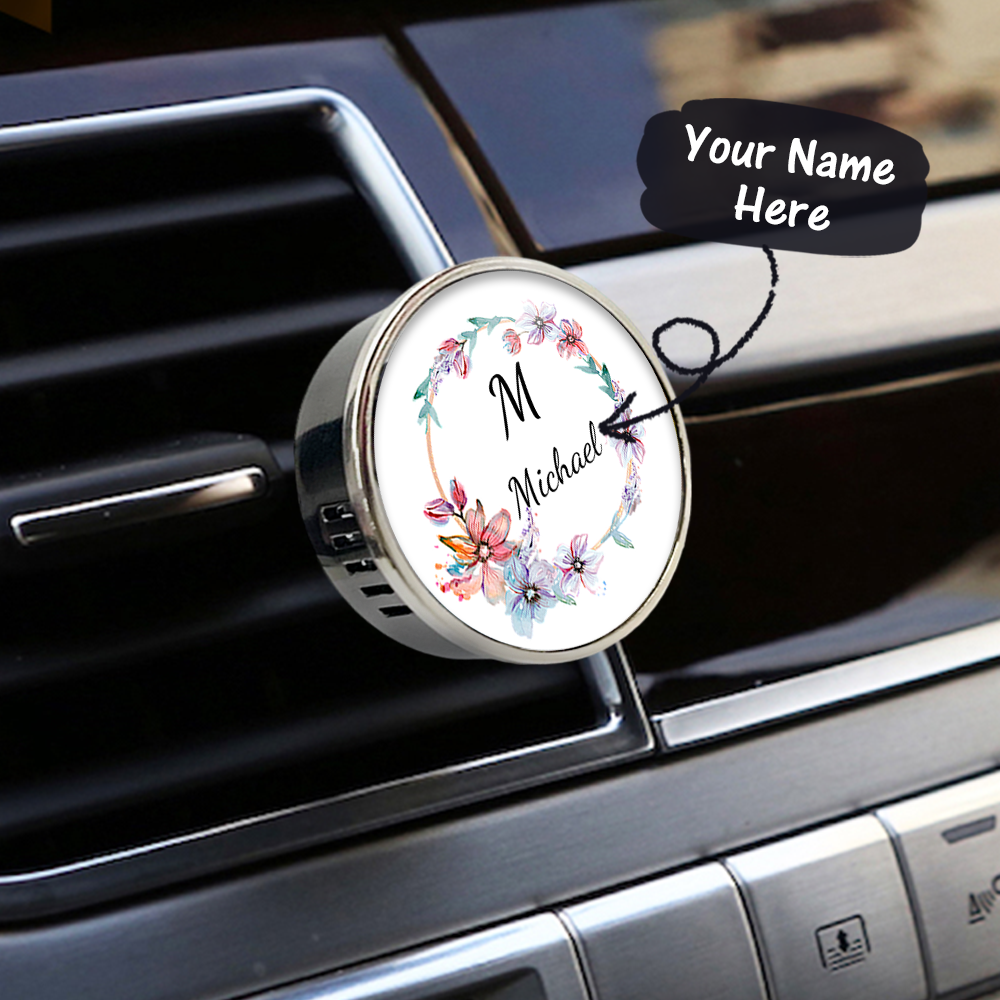 Car air freshener with floral design and customizable name on a car vent.
