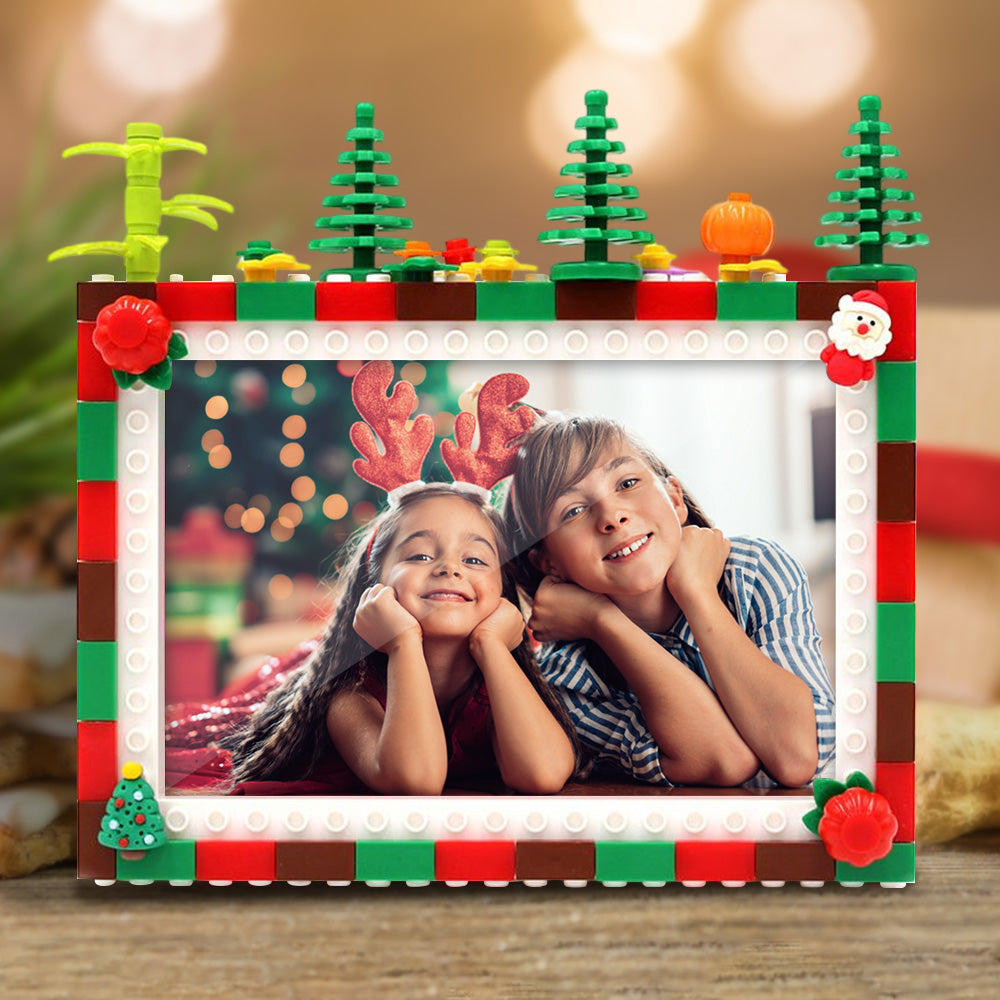 Children's photo inside a decorative Lego frame with Christmas trees and Santa Claus on a blurred background.