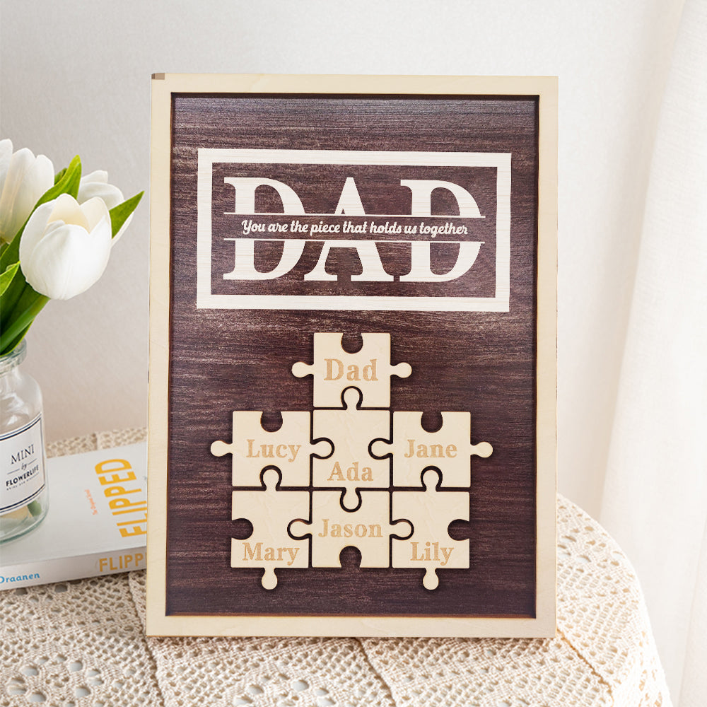 Wooden puzzle frame with 'DAD' and names on a white surface with flowers.