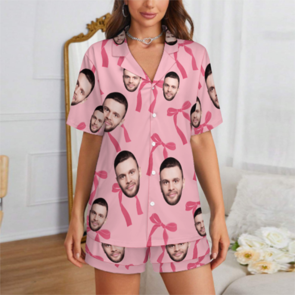 Person wearing pink pajama set with printed faces in a room.
