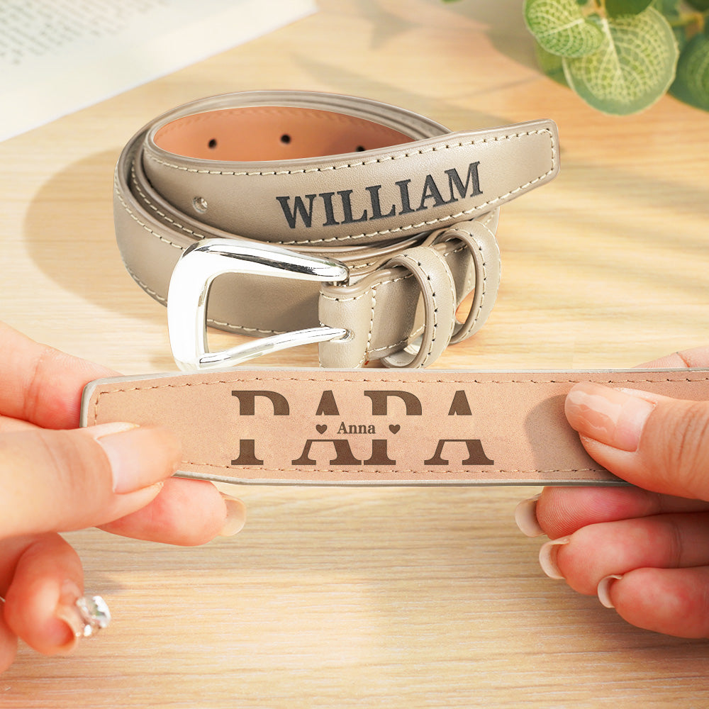 Personalized leather belt with engraved text held by hands on a wooden surface