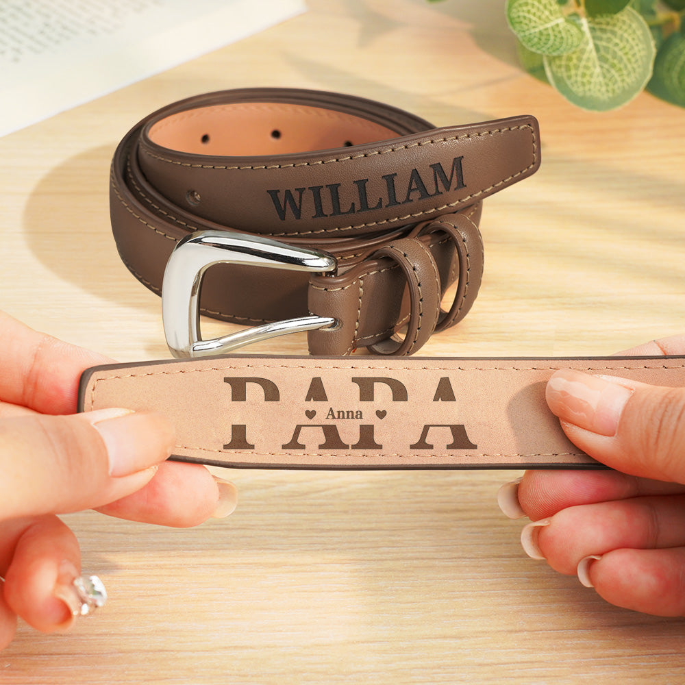 Brown leather belt with engraved name 'WILLIAM' on a wooden surface.