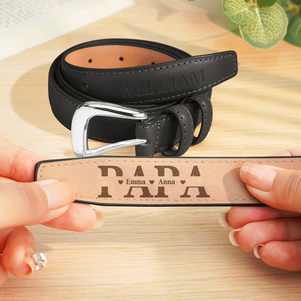 Black leather belt with engraved text held by hands on a wooden surface