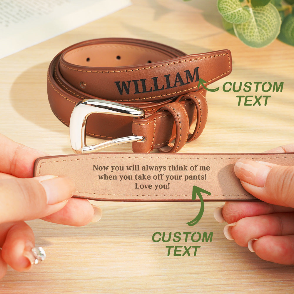 Brown leather belt with 'WILLIAM' engraved on it, held by hands on a wooden surface.