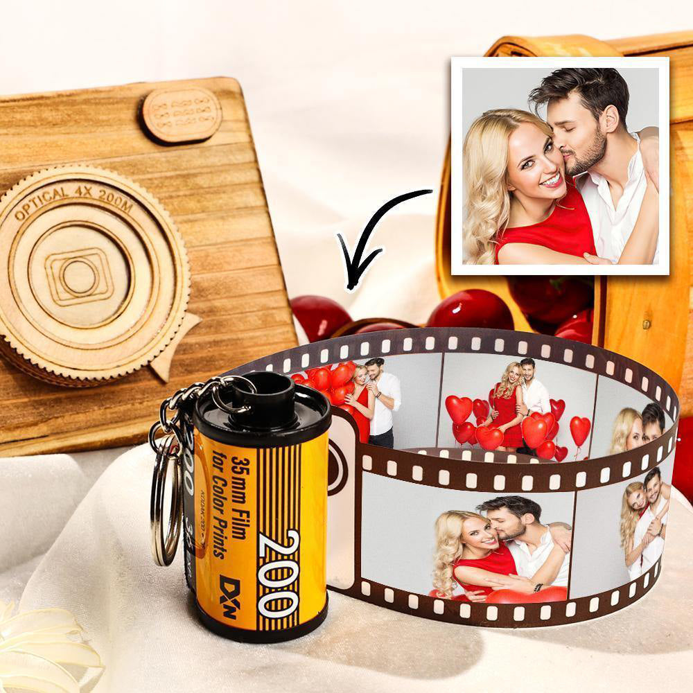 Film canister keychain with photo roll displaying images of a couple, on a wooden board.