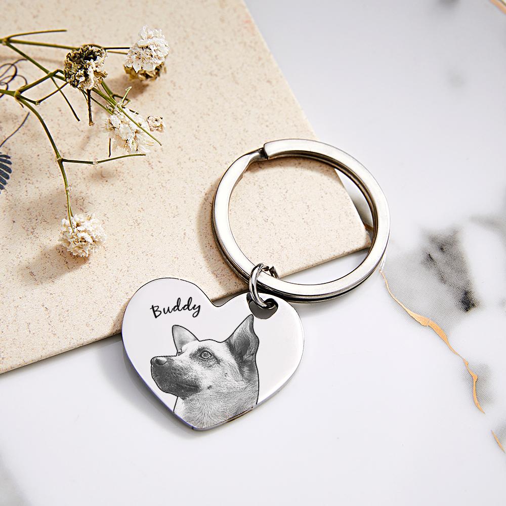 Heart-shaped keychain with engraved dog photo and name 'Buddy' on a marble surface.