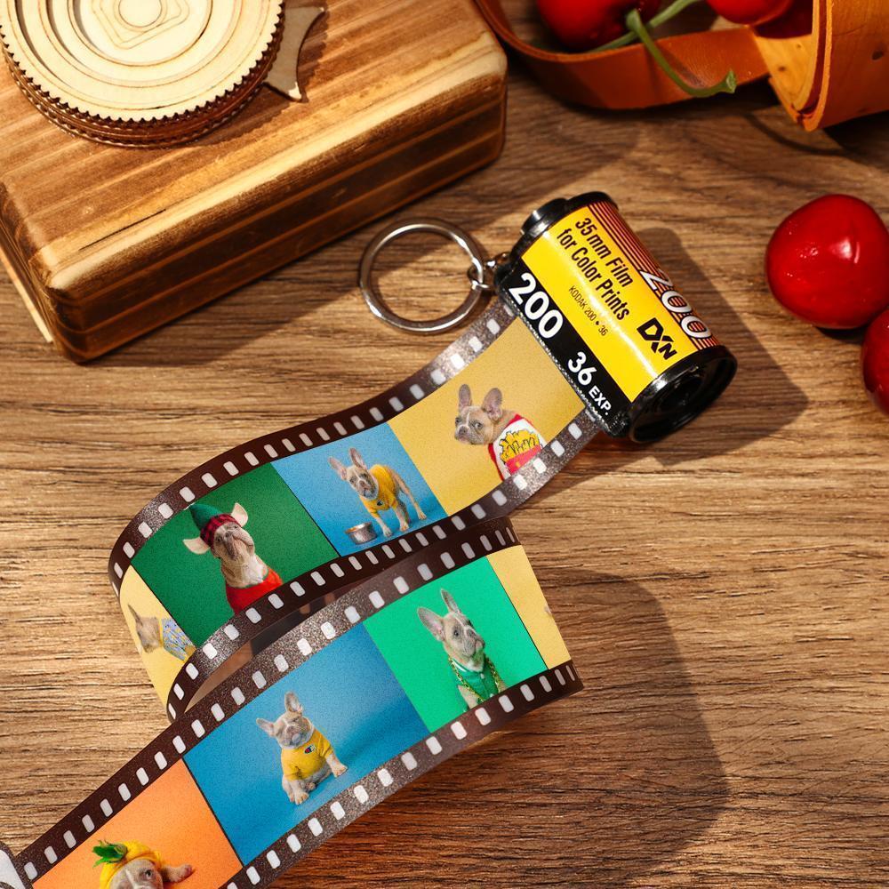 Film roll keychain with dog-themed images on a wooden surface