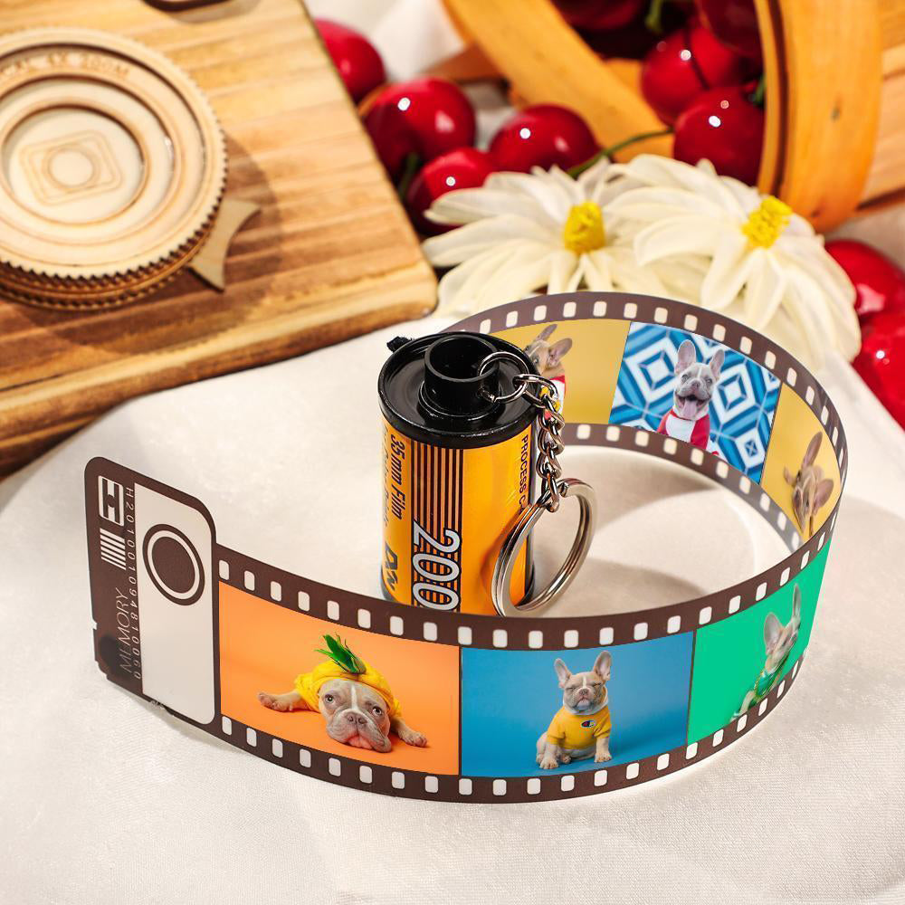 Film reel keychain with dog photos on a white surface with cherries and flowers in the background