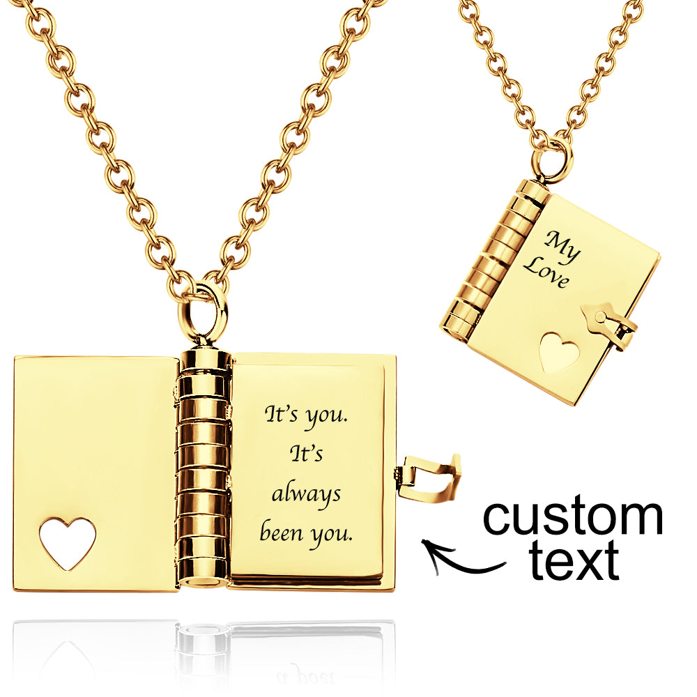 Gold necklace with open book pendant featuring engraved text on a white background