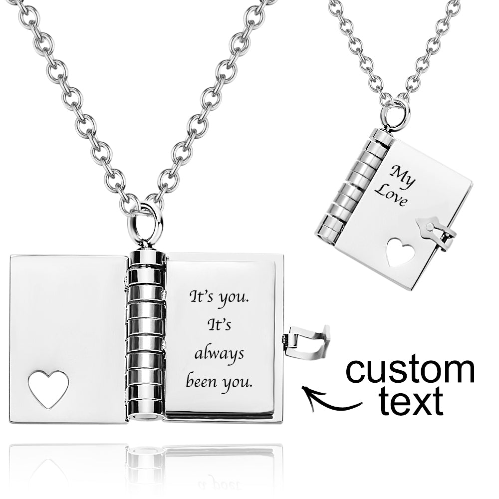 Silver necklace with an open book pendant and engraved text on a white background