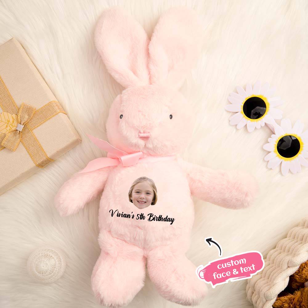 Pink bunny plush toy with customizable face and text on a soft surface with flowers and a gift.