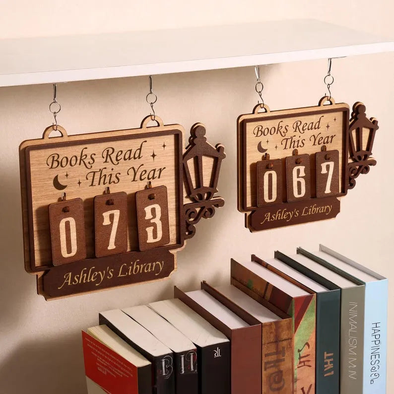 Wooden plaque with 'Books Read This Year' counter and books below on a beige background