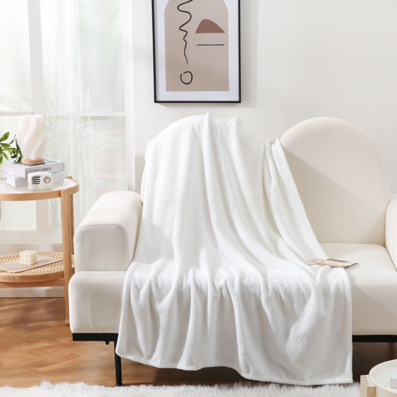 White blanket draped over a white sofa in a living room setting.