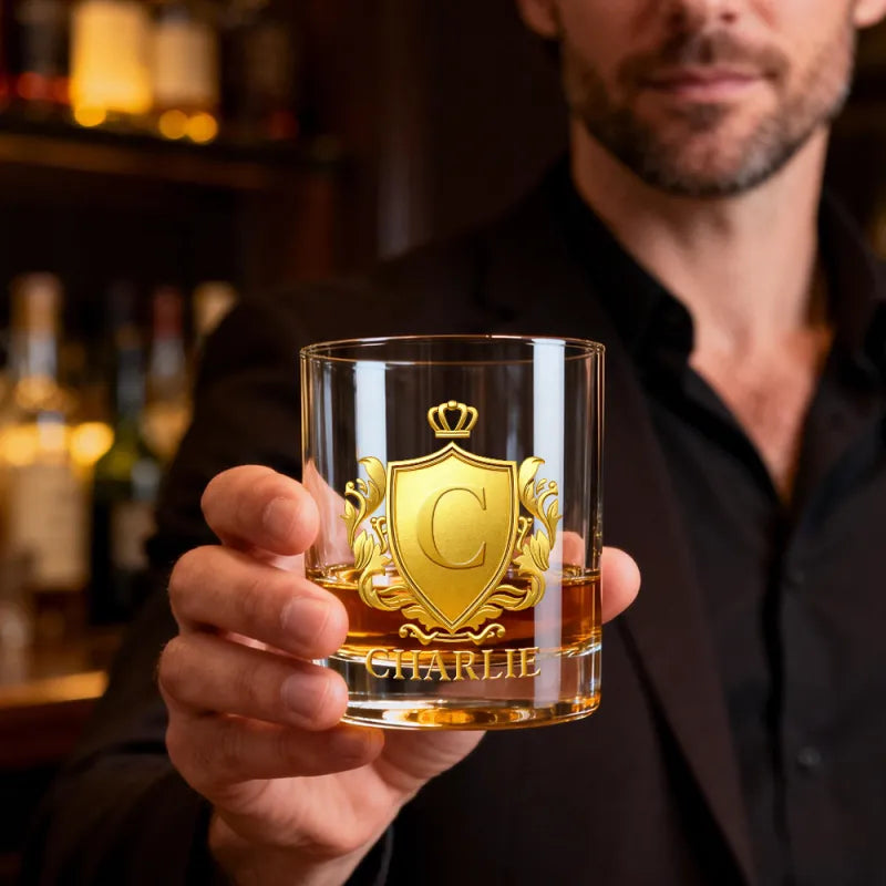 Man holding a glass with a gold emblem and 'Charlie' branding in a bar setting