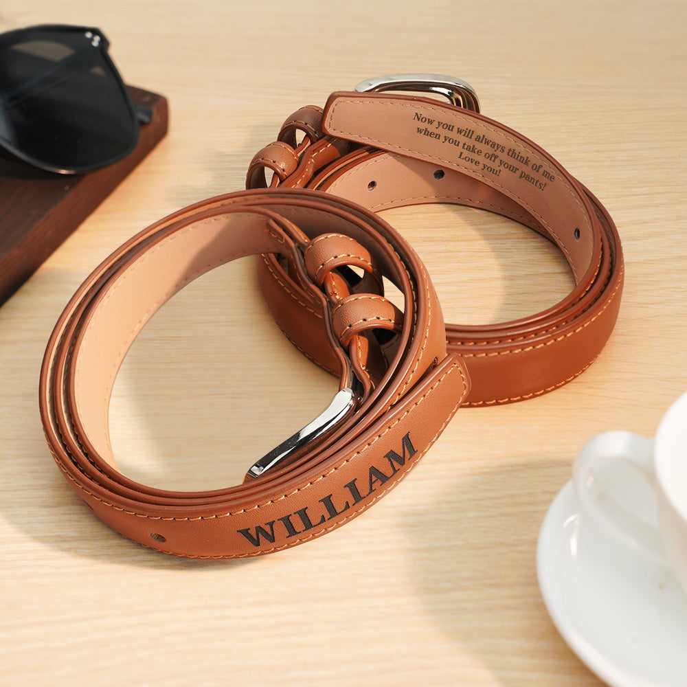 Brown leather belt with engraved text on a wooden surface