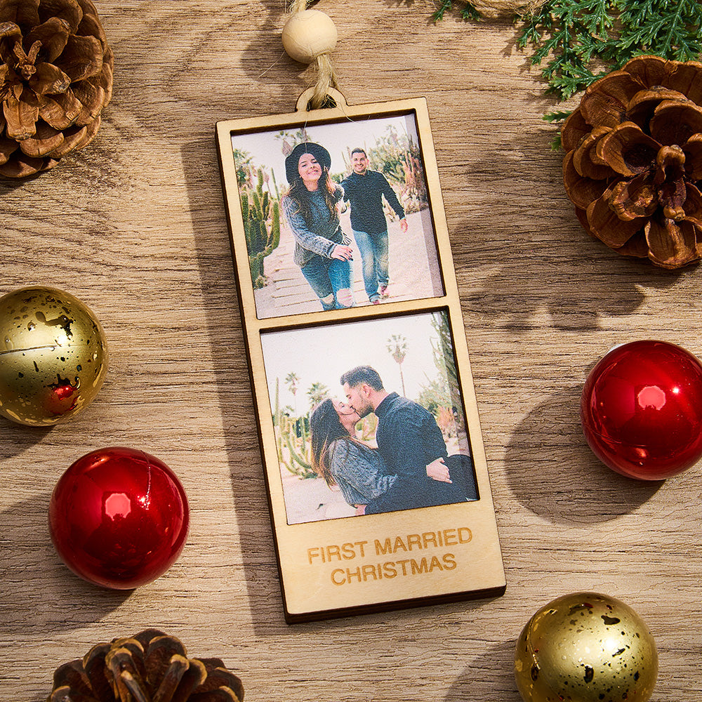 Wooden photo ornament with couple's photos and 'First Married Christmas' text, surrounded by Christmas decorations on a wooden surface.