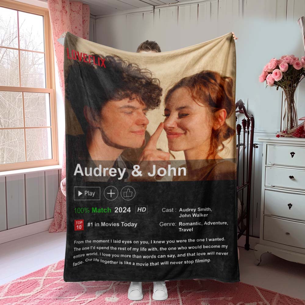 Blanket with a printed design of two people and text, held by a person in a room.