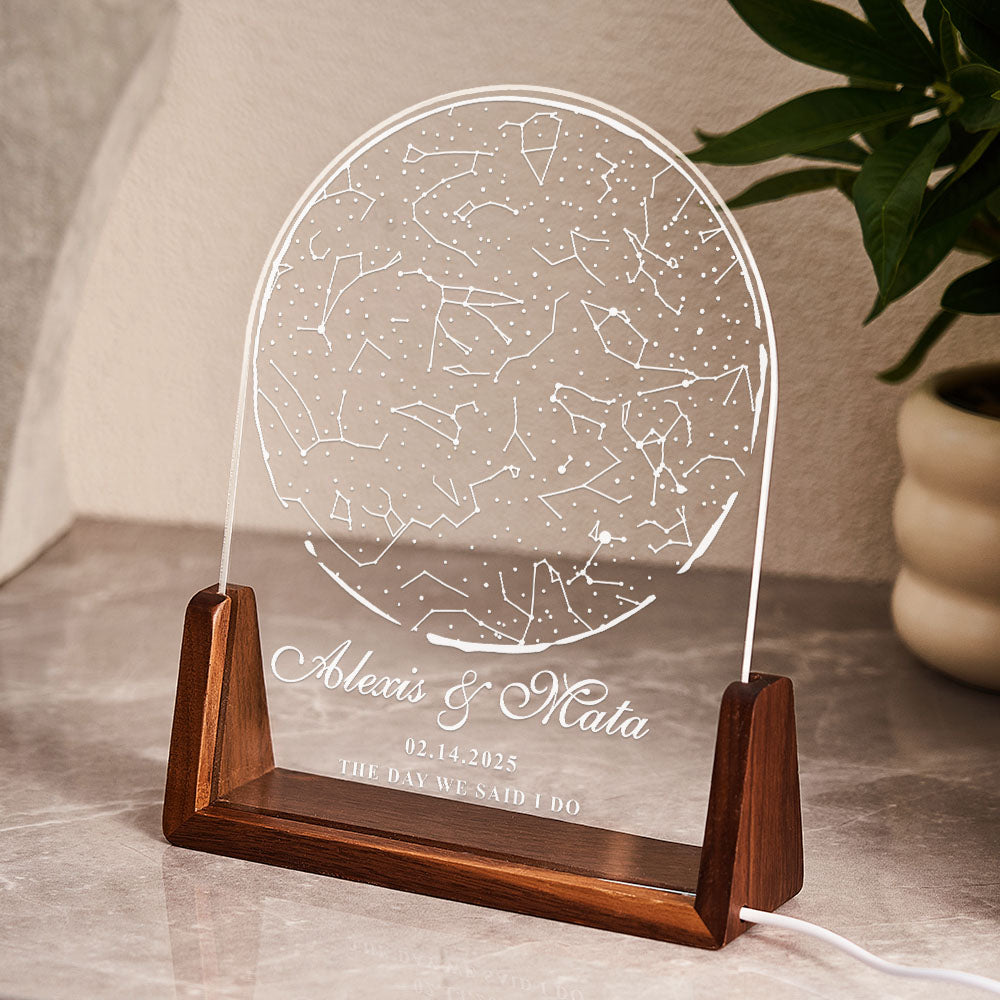 Decorative lamp with engraved constellation design on a wooden base, placed on a surface with a plant in the background.